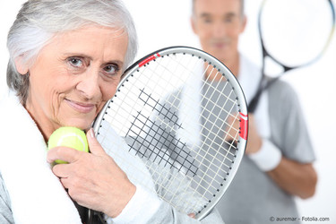Ältere Frau mit Tennisball und Schläger