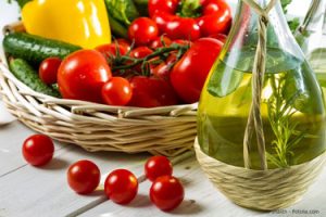 Ein Korb mit Tomaten, anderem Gemüse und Öl
